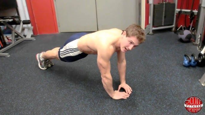 En man utför diamantarmhävningar i ett gym.